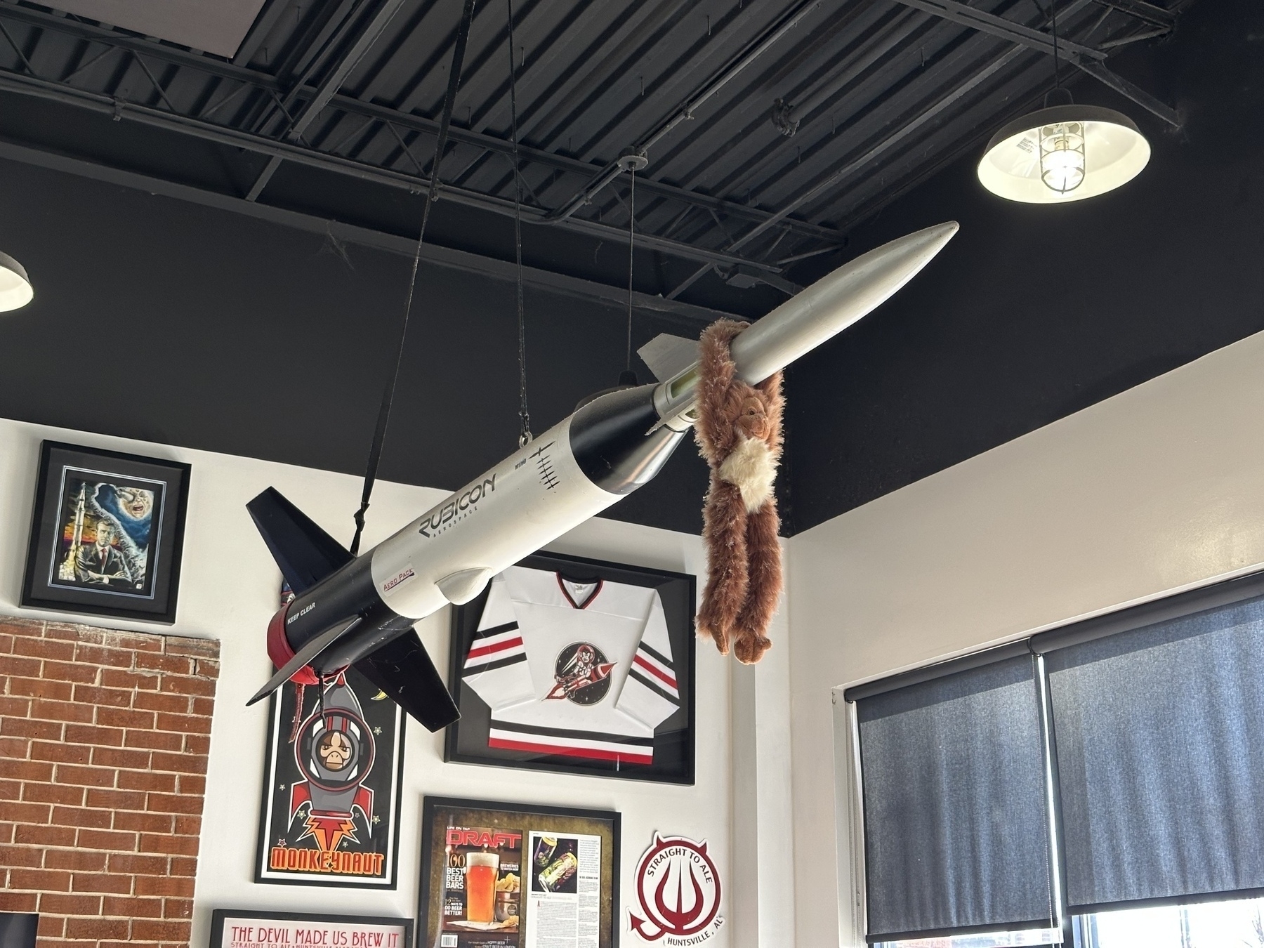Stuffed monkey holding onto large model rocket hanging from the ceiling